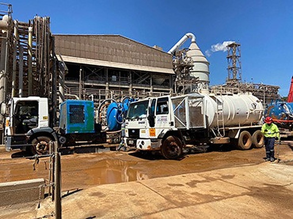 Dois caminhões vácuo estacionados em planta industrial