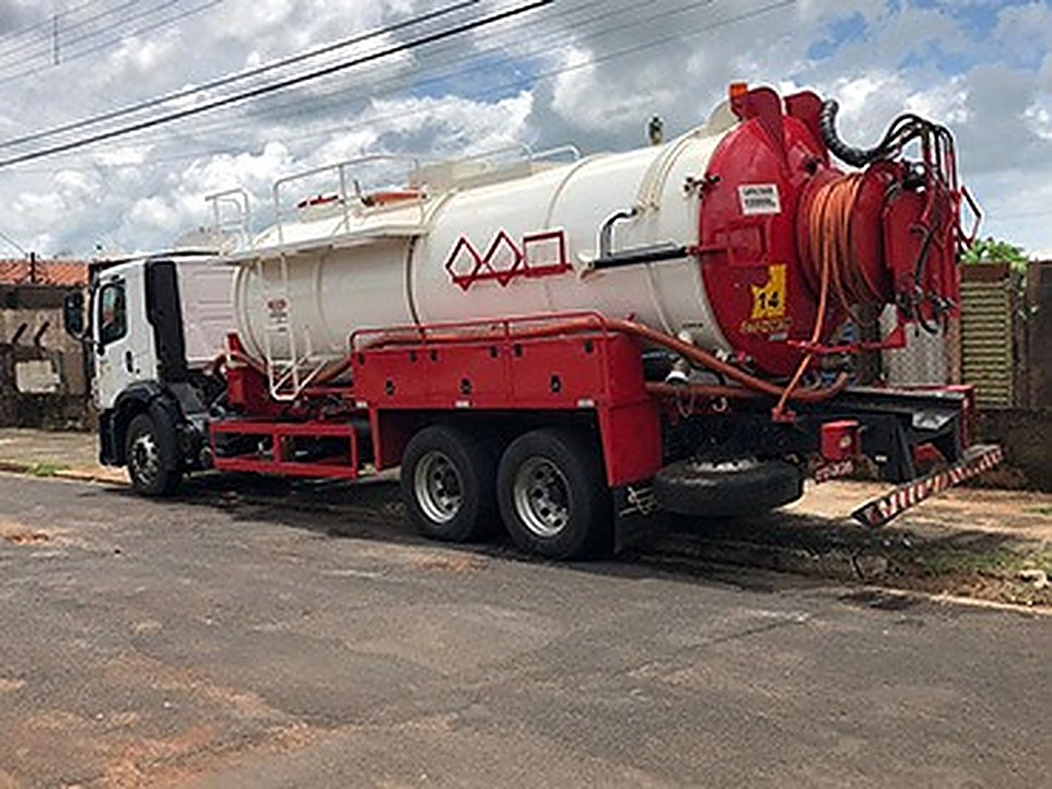 Caminhão vácuo vermelho e branco estacionado